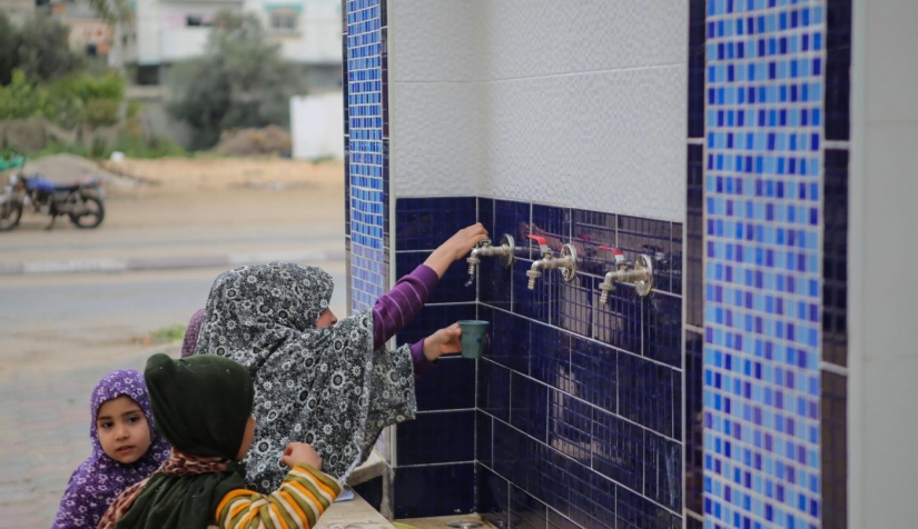 أطفال فلسطينيون يشربون المياه من صنبور عام بمخيم النصيرات في غزة.