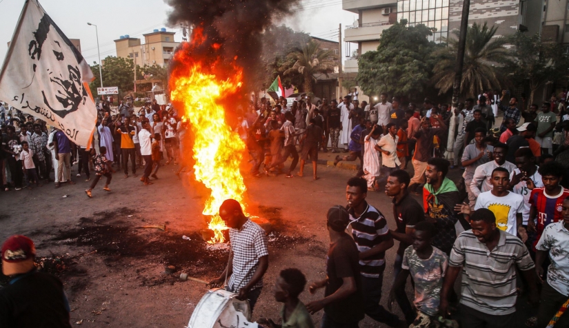محتجون سودانيون يرددون الهتافات وسط الإطارات المحروقة خلال مظاهرة في العاصمة الخرطوم في 26 تشرين الأول/ أكتوبر.