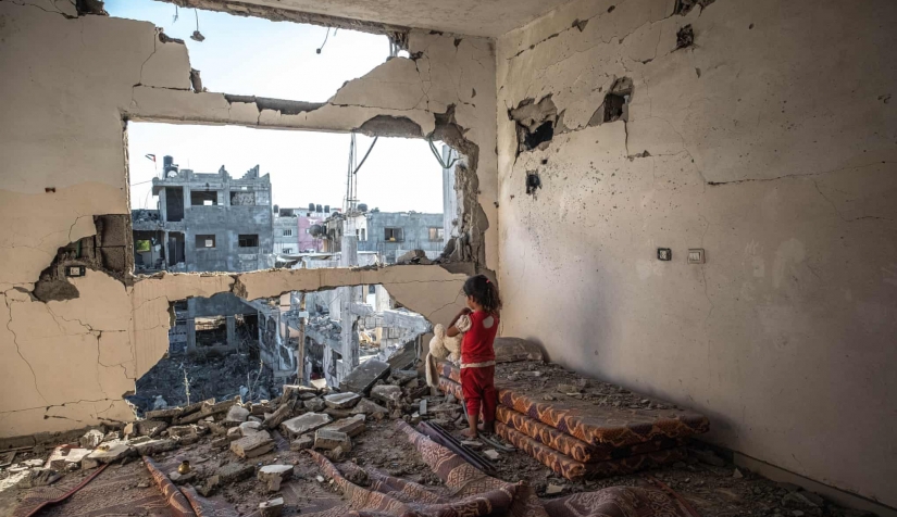 رغد (4 سنوات) تقفُ وسط أنقاض منزلها في بيت حانون بقطاع غزة المحاصر.