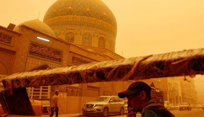 رجل يدخن سجائر في أثناء العاصفة الرملية في بغداد بالعراق