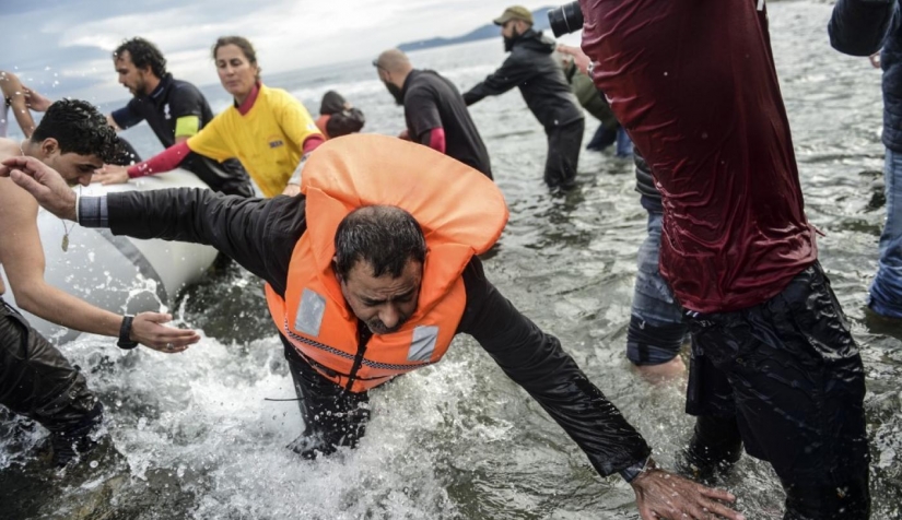اللاجئون يترجلون من القارب عند جزيرة ليسبوس اليونانية بعد عبورهم بحر إيجة من تركيا