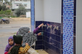 أطفال فلسطينيون يشربون المياه من صنبور عام بمخيم النصيرات في غزة.