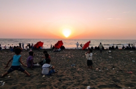 يمنيون يشاهدون غروب الشمس من شاطئ في الحديدة.