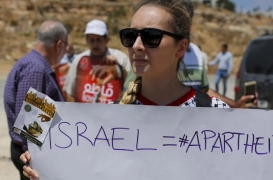 امرأة تتظاهر عند حاجز عوفر في الضفة الغربية المحتلة وتدعو الفلسطينيين لمقاطعة الواردات الإسرائيلية
