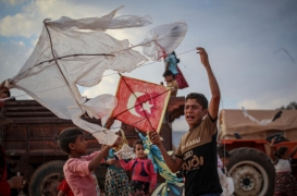 أطفال يحاولون رفع طائرات ورقية تحمل علم تركيا في مخيم "تيه" للاجئين قرب الحدود التركية