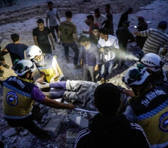 أعضاء من منظمة الخوذ البيضاء ينقذون رجلا من تحت الأنقاض بعد غارة جوية في إدلب