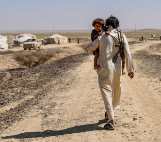 أب نازح يحمل ابنه ويسير نحو خيمتهم المؤقتة في ضواحي مأرب وسط اليمن