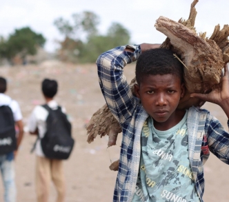يحمل فضل بكار - 13 عامًا - الحطب إلى خيمته، ترك بكار المدرسة عام 2016 عندما اندلع القتال في قريته واضطر للفرار، والآن يقضي معظم وقته في مساعدة أسرته بالقيام بالأعمال اليومية