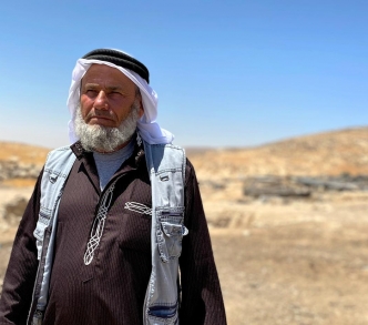 يقف علي جبارين في قرية جنبا إحدى قرى مسافر يطا التي تواجه تهجيرًا إسرائيليًا وشيكًا