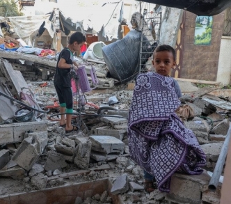 أطفال فلسطينيون ينقذون أمتعتهم من وسط حطام منزلهم الذي دُمر في أثناء العدوان الأخير