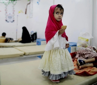فتاة تقف بجوار أختها التي تتلقى العلاج في إحدى مستشفيات صنعاء حيث مات 10 أطفال نتيجة الأدوية الفاسدة