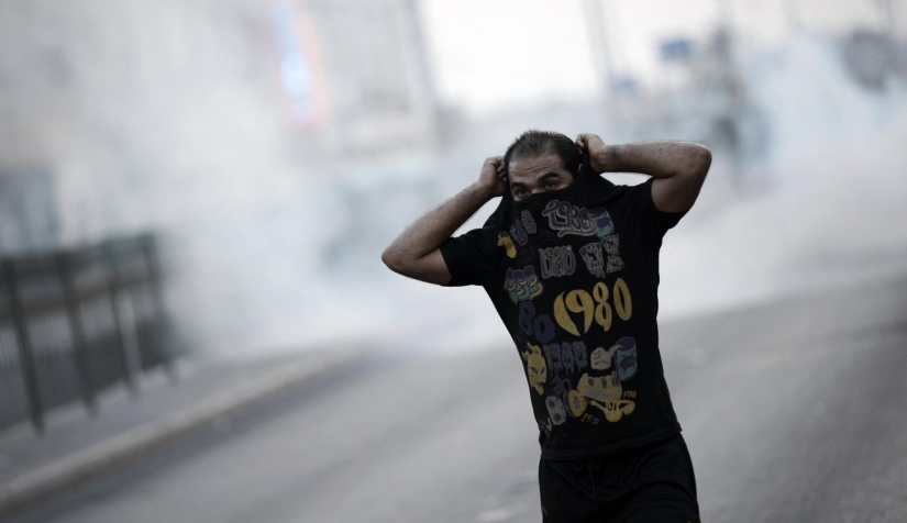 متظاهر بحريني يجري للاحتماء من الغاز المسيل للدموع الذي أطلقته شرطة مكافحة الشغب خلال اشتباكات في احتجاج يوم 28 من أغسطس/آب 2015