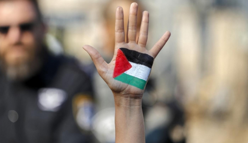 متظاهر يرفع يده المرسوم عليها علم فلسطين في مظاهرة ضد الاحتلال الإسرائيلي والاستيطان