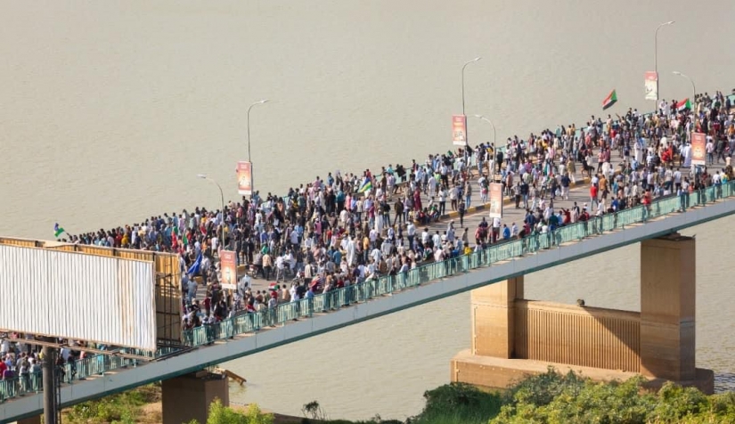 محتجون يعبرون الجسر باتجاه القصر الرئاسي بوسط العاصمة الخرطوم.