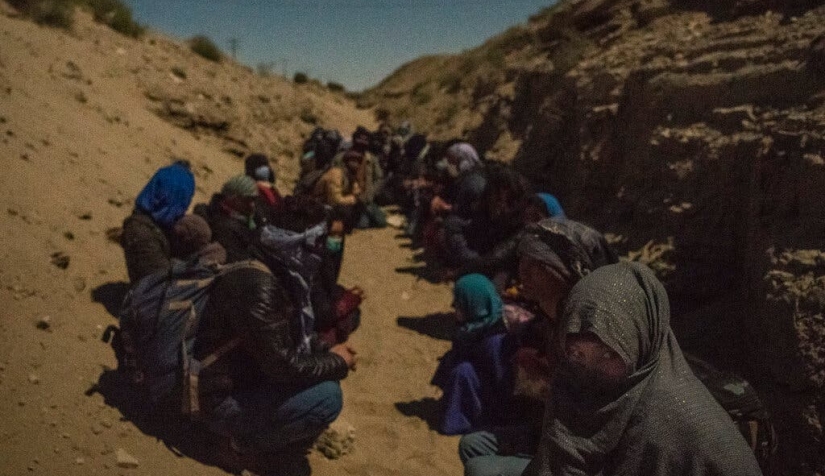على بعد بضع مئات الأمتار فقط من الحدود الإيرانية، مهاجرون يجلسون في خندق في انتظار تلقي الضوء الأخضر من المهربين للتحرك، بالقرب من مدينة زرنج الأفغانية، في تشرين الثاني/ نوفمبر.