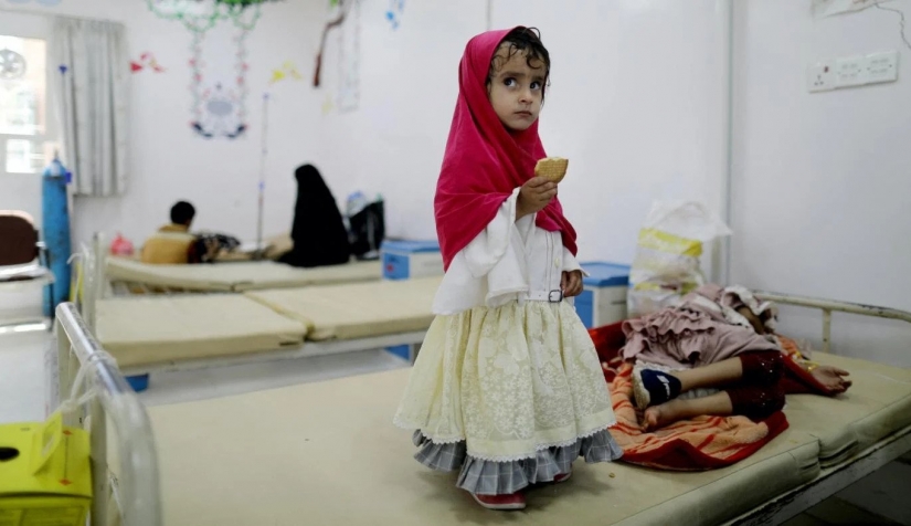 فتاة تقف بجوار أختها التي تتلقى العلاج في إحدى مستشفيات صنعاء حيث مات 10 أطفال نتيجة الأدوية الفاسدة