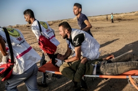 مسعفون فلسطينيون يحملون متظاهرًا مصابًا في غزة، في 27 أيلول/ سبتمبر.