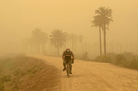 رجل يقود دراجته في أثناء عاصفة رملية في البصرة بالعراق