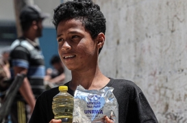 صبي يحمل زجاجة زيت وعبوة حليب من وكالة الأمم المتحدة للاجئين الفلسطينيين في غزة.