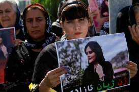 سيدة تحمل لافتة احتجاجًا على وفاة مهسا أميني أمام مقر الأمم المتحدة في أربيل بالعراق