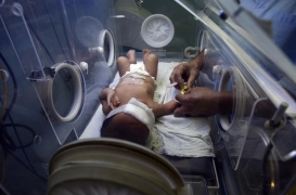 ممرضة فلسطينية تقدم الرعاية الطبية لطفل حديث الولادة في حاضنة بمستشفى الشفاء في غزة.