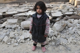 طفلة سورية تقف وسط حطام المنازل في بلدة جنديرس.