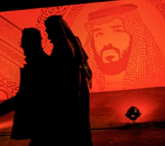 سعوديون يسيرون بجوار صورة لولي العهد السعودي محمد بن سلمان في الرياض