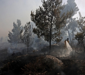 رجل إطفاء يطفئ حريق الغابة بالقرب من قرية أبو غوش ذات الأغلبية الفلسطينية
