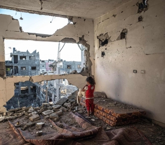 رغد (4 سنوات) تقفُ وسط أنقاض منزلها في بيت حانون بقطاع غزة المحاصر.