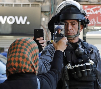 فلسطينية تلتقط صورة لأحد أفراد قوات الأمن الإسرائيلية الذي كان بصدد التقاط صورة لها دون إذن في أحد شوارع القدس، 16 كانون الأول/ ديسمبر 2017. 