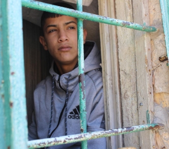 علي قنيبي - 14 عامًا - من نافذة منزله في حي الشيخ جراح حيث يقبع قيد الإقامة الجبرية منذ 7 أشهر