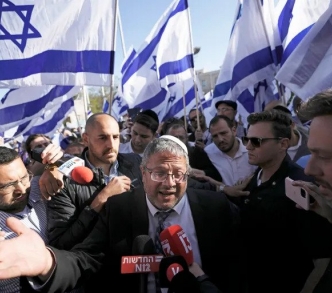 إيتمار بن غفير محاطًا بنشطاء اليمين المتطرف الإسرائيلي ويرفعون العلم الإسرائيلي في أثناء حديثهم مع الإعلام