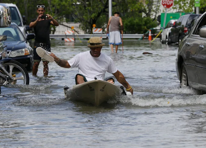 خوان كارلوس سانشيز يجدف بالقارب بحذائه  في شارع غمرته المياه في ميامي بيتش في العام الماضي.