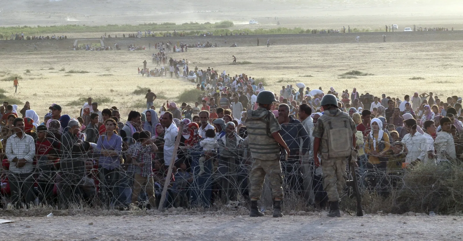 turkish-soldiers-stand-guard-syrian-refugees-wait-behind-border-fences