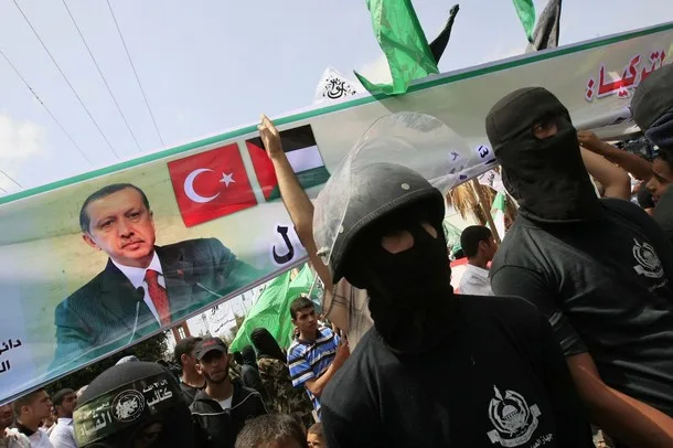 masked_hamas_militants_hold_a_banner_bearing_the_portrait_of_turkish_prime_minister_recep_tayyip_erdogan_and_the_turkish_and_palestinian_flags_during_a_rally_organized_by_the_islamist
