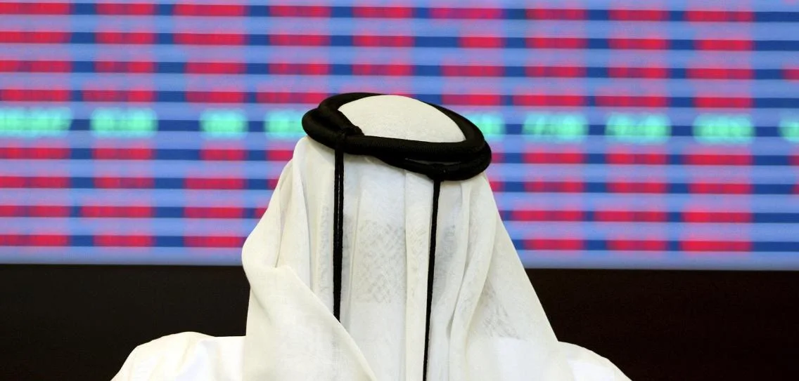 a-trader-looks-at-share-prices-on-an-electronic-display-at-the-doha-stock-ex-2