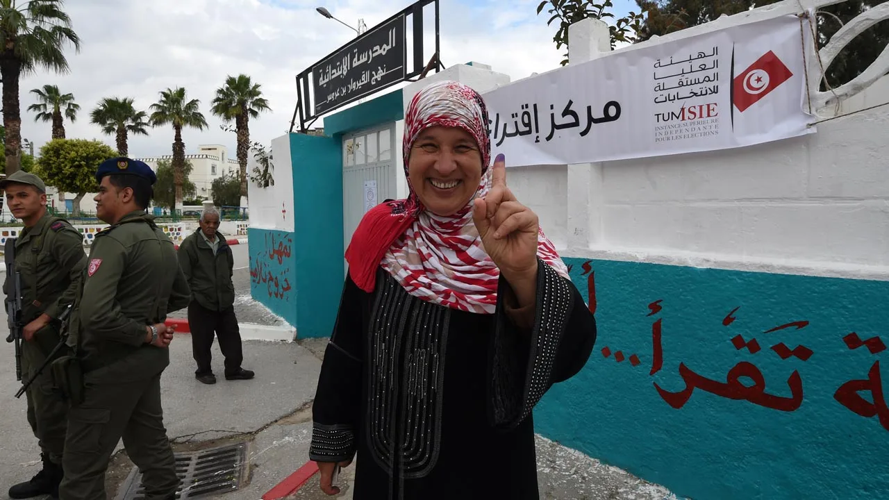 a_tunisian_woman_voter_showcases_her_ink-stained_finger_after_voting_in_municipal_elections_in_may