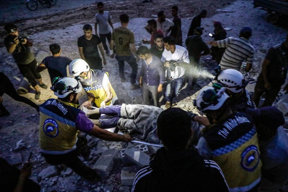 أعضاء من منظمة الخوذ البيضاء ينقذون رجلا من تحت الأنقاض بعد غارة جوية في إدلب