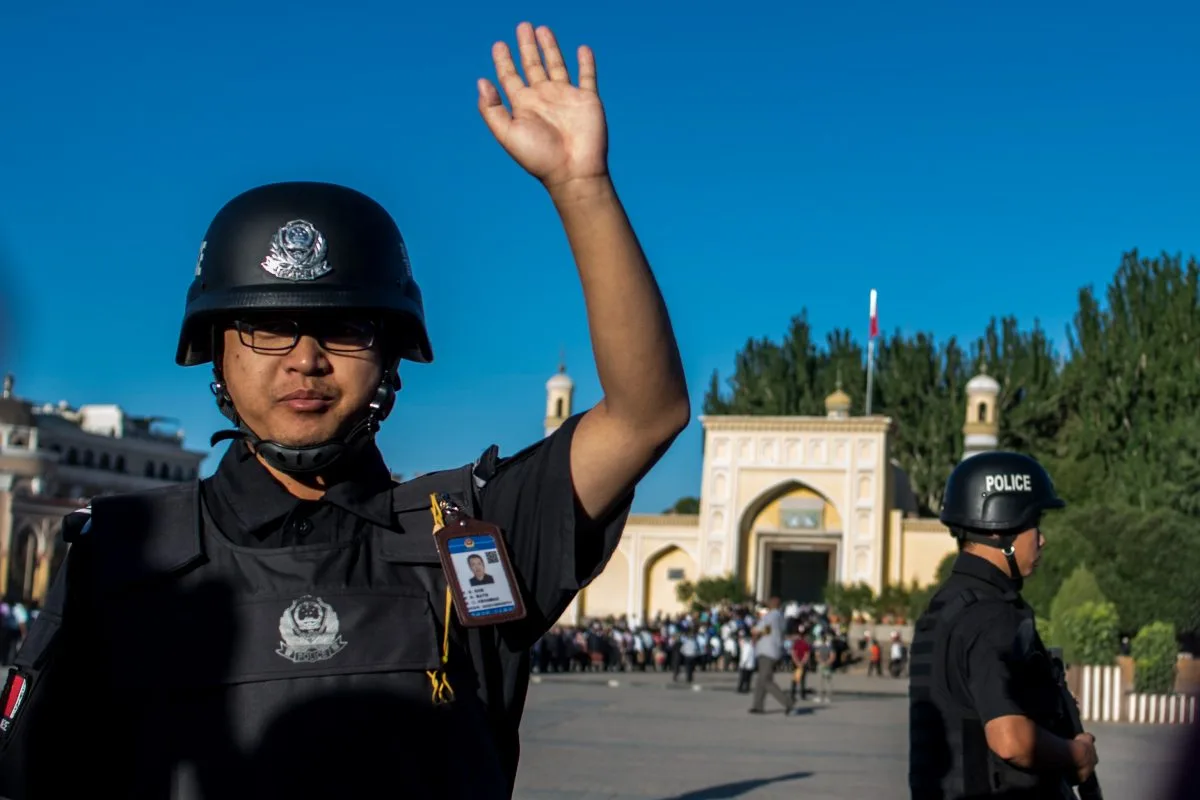 ضابط شرطة يشير إلى وصول المصلين للمسجد في منطقة شينجيانغ