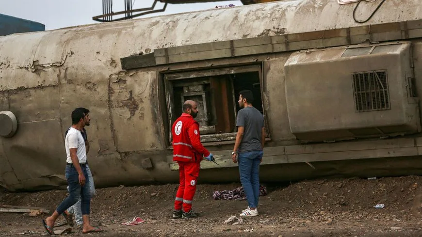 مسعف يتحدث مع رجل بجوار عربة قطار انقلبت في موقع حادث سكة حديدية في مدينة طوخ بمحافظة القليوبية بوسط دلتا النيل في مصر في 18 نيسان/ أبريل سنة 2021.