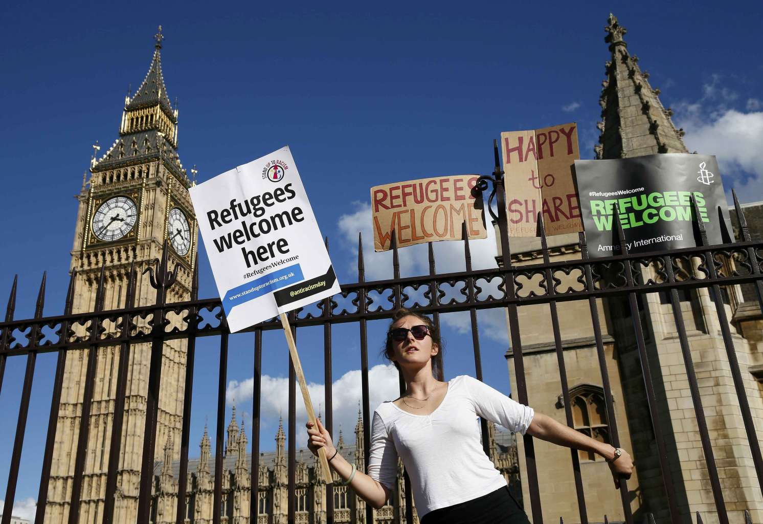 متظاهرة تحمل لافتة خارج مقر البرلمان البريطاني للترحيب باللاجئين