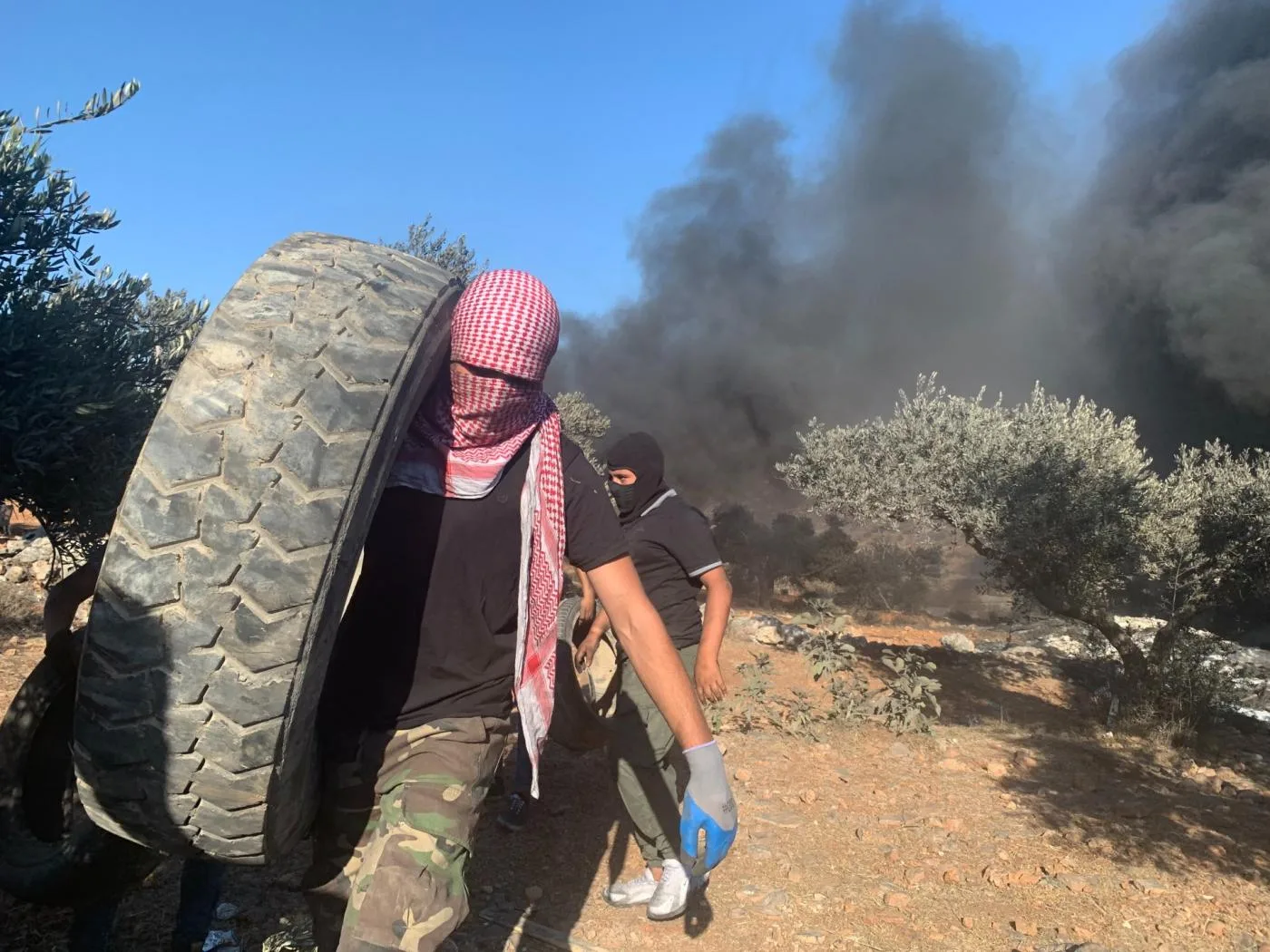 رجال فلسطينيون يستخدمون الإطارات المشتعلة للاحتجاج ضد الاستيطان غير القانوني في بيتا