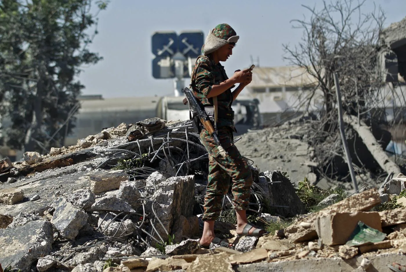 جندي حوثي يقف وسط أنقاض مبنى تم تدميره على إثر غارة جوية للتحالف بقيادة السعودية استهدفت مطار صنعاء الدولي في 21 كانون ثاني/ ديسمبر 2021.