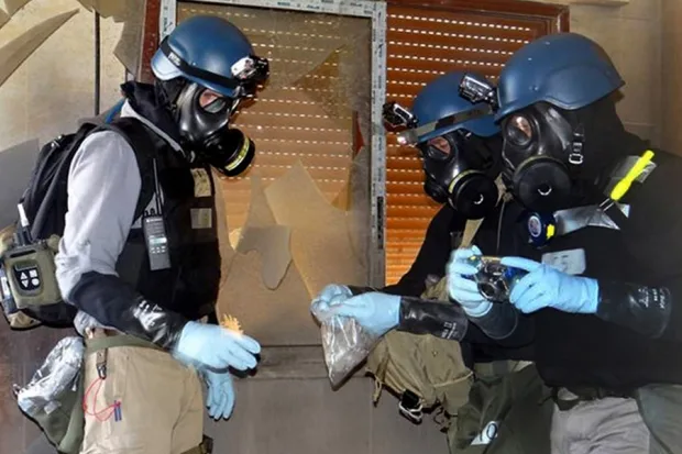 خبير أسلحة كيميائية بالأمم المتحدة يحمل كيسًا بلاستيكيًا يحتوي عينات من أحد مواقع هجوم مزعوم بالأسلحة الكيميائية في حي عين ترما بدمشق، في 29 آب/ أغسطس 2013.