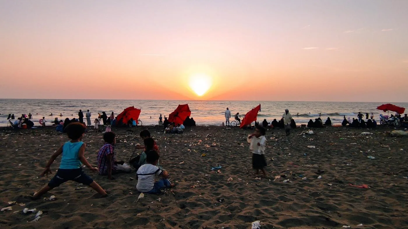 يمنيون يشاهدون غروب الشمس من شاطئ في الحديدة.