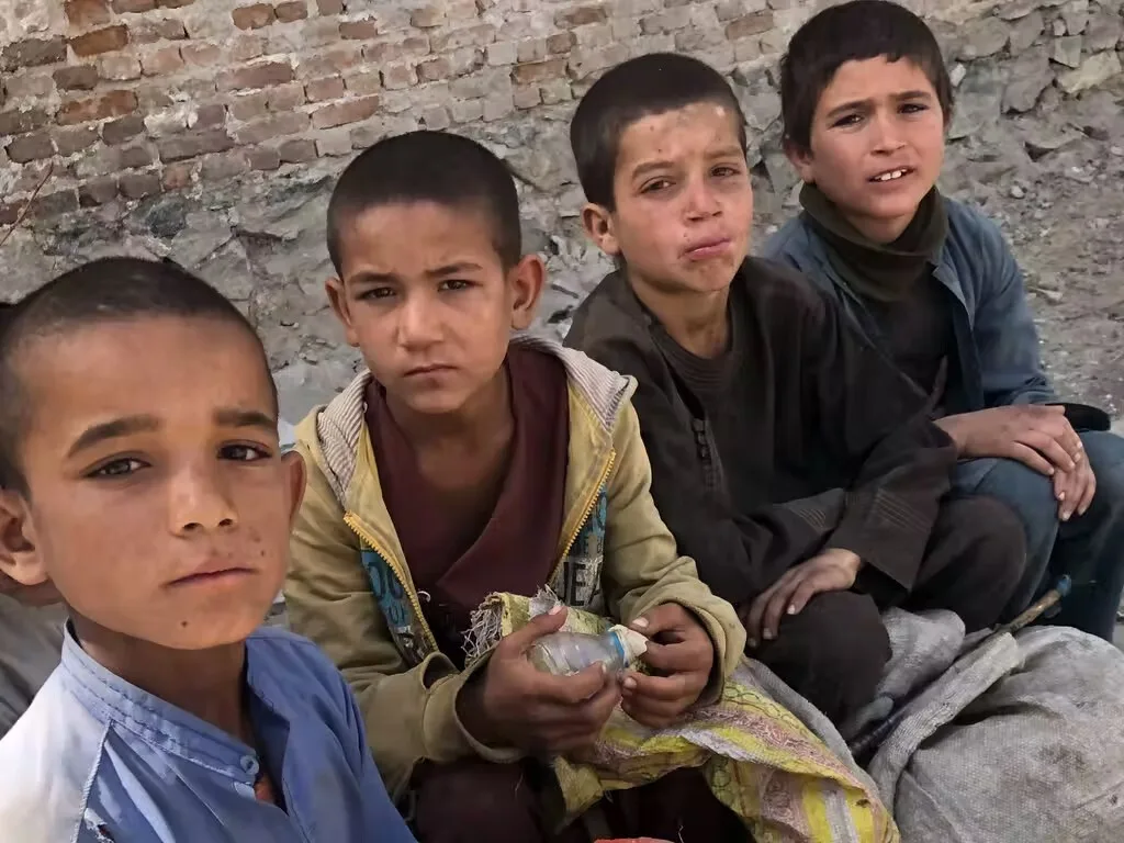 4 صبية يستريحون من البحث في مكبات القمامة عن الزجاجات والعلب في كابول