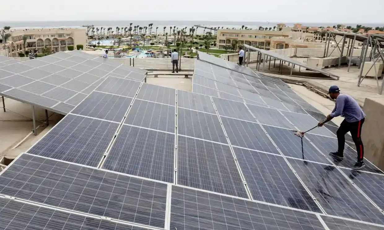 رجل ينظف الخلايا الشمسية فوق أحد فنادق مدينة شرم الشيخ حيث ستُعقد قمة المناخ في نوفمبر.