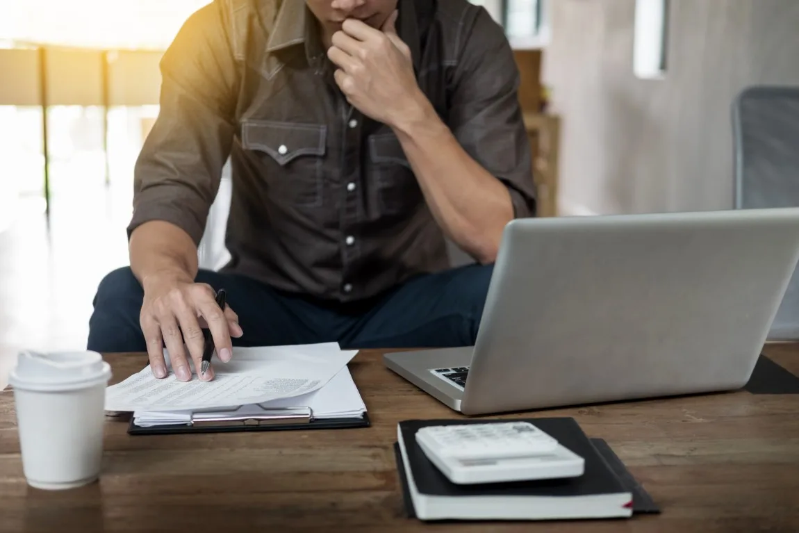 man-thinking-laptop-papers