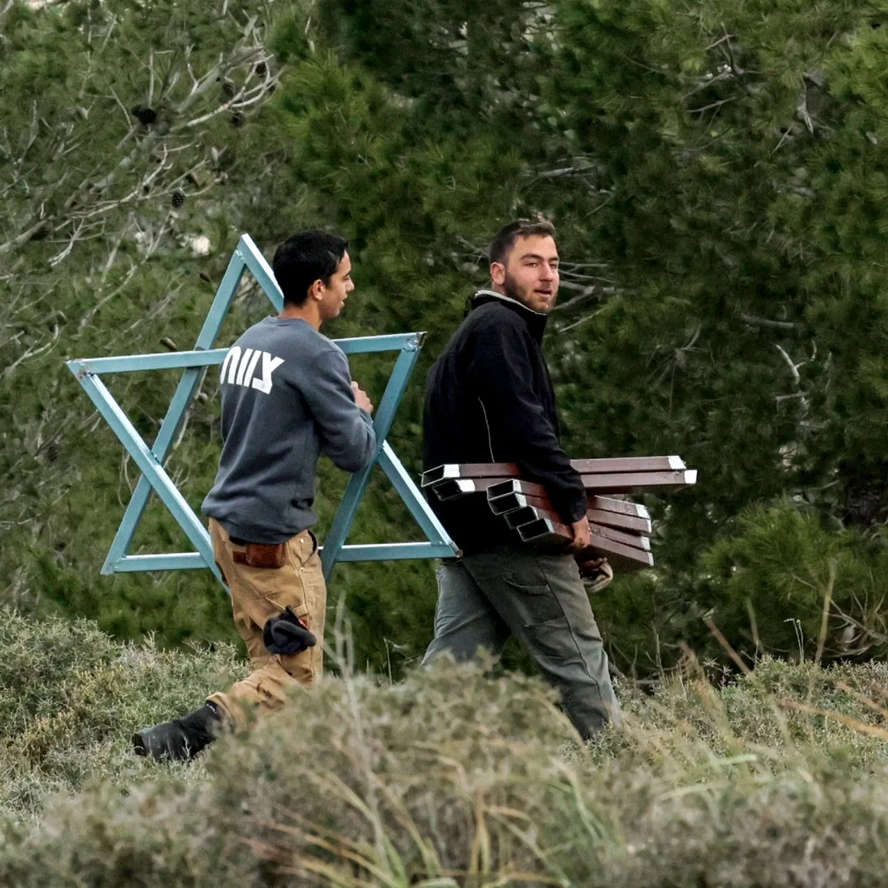 مستوطنون إسرائيليون يحملون نجمة داوود معدنية نحو بؤرة استيطانية جديدة قرب قرية في الضفة الغربية