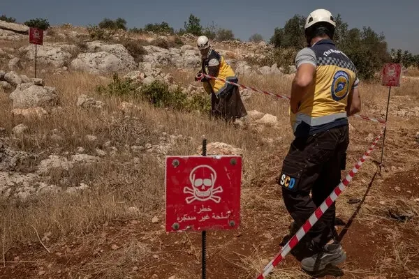 المتطوعون الذي يعملون مع منظمة الخوذ البيضاء يقيمون منطقة تحذير حول قنبلة عنقودية مشتبه بها في منطقة ترمانين هذا الشهر